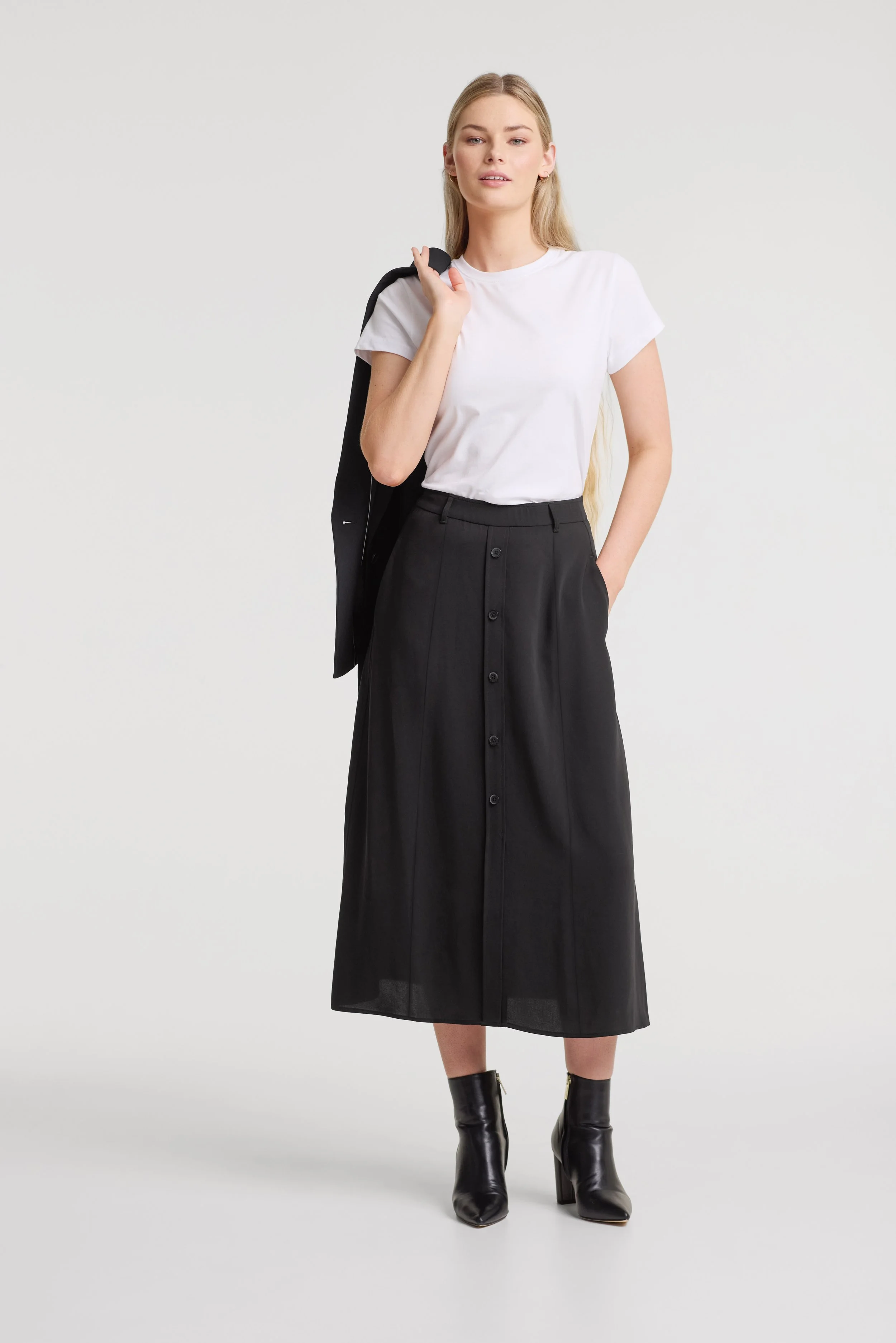Two smiling employees, a man and a woman, standing in a library or books storage area, both wearing uniforms with name tags that say 'Jon Monsir'.