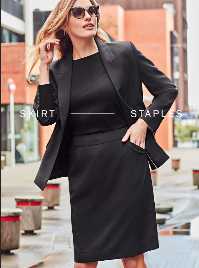 Woman wearing a navy blue tailored blazer over a white top against a beige background.