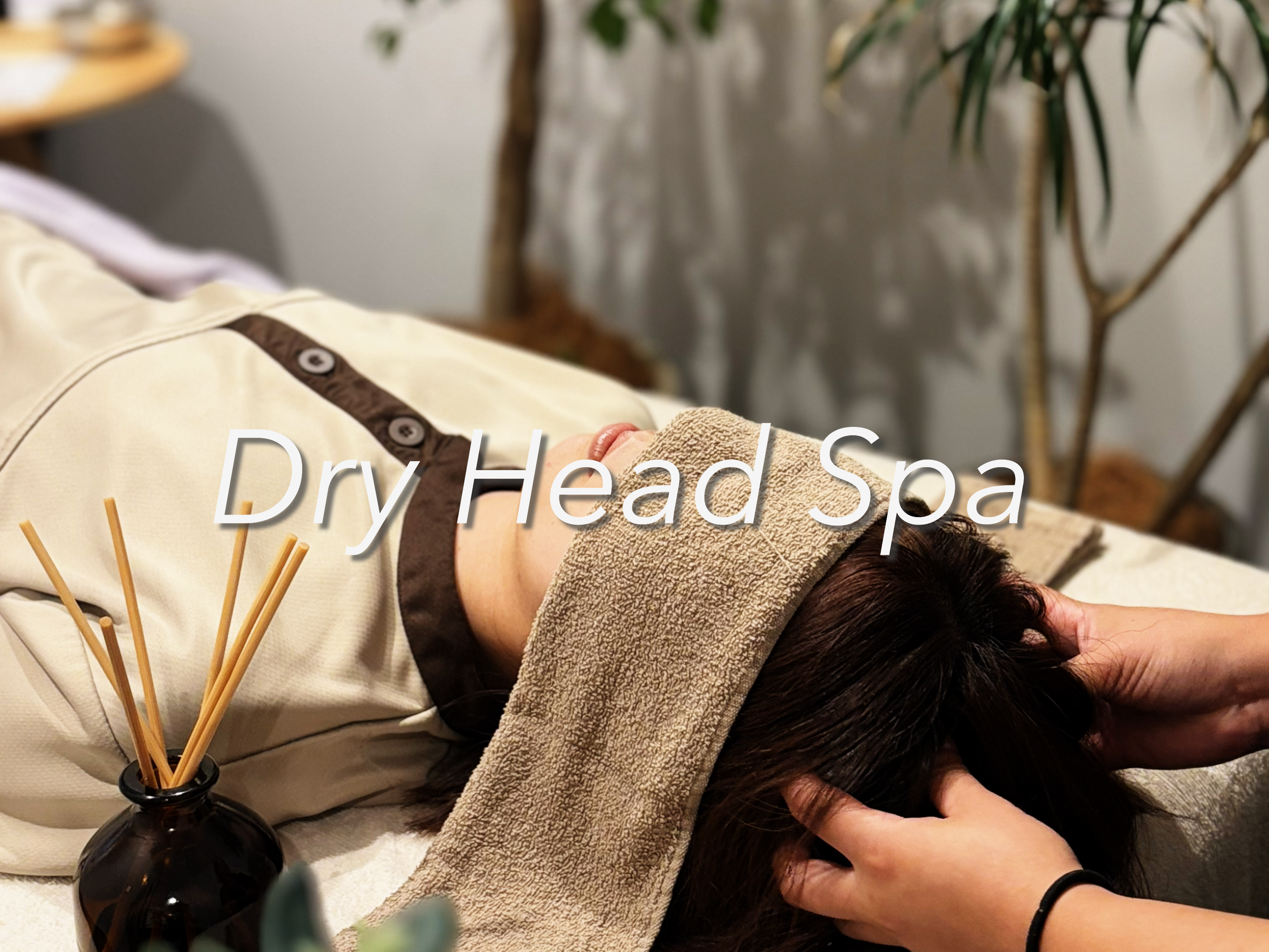 アロマオイルとリードディフューザーのあるリラクゼーションルームで、リラクゼーションマッサージを受けている女性の後ろ側の様子。