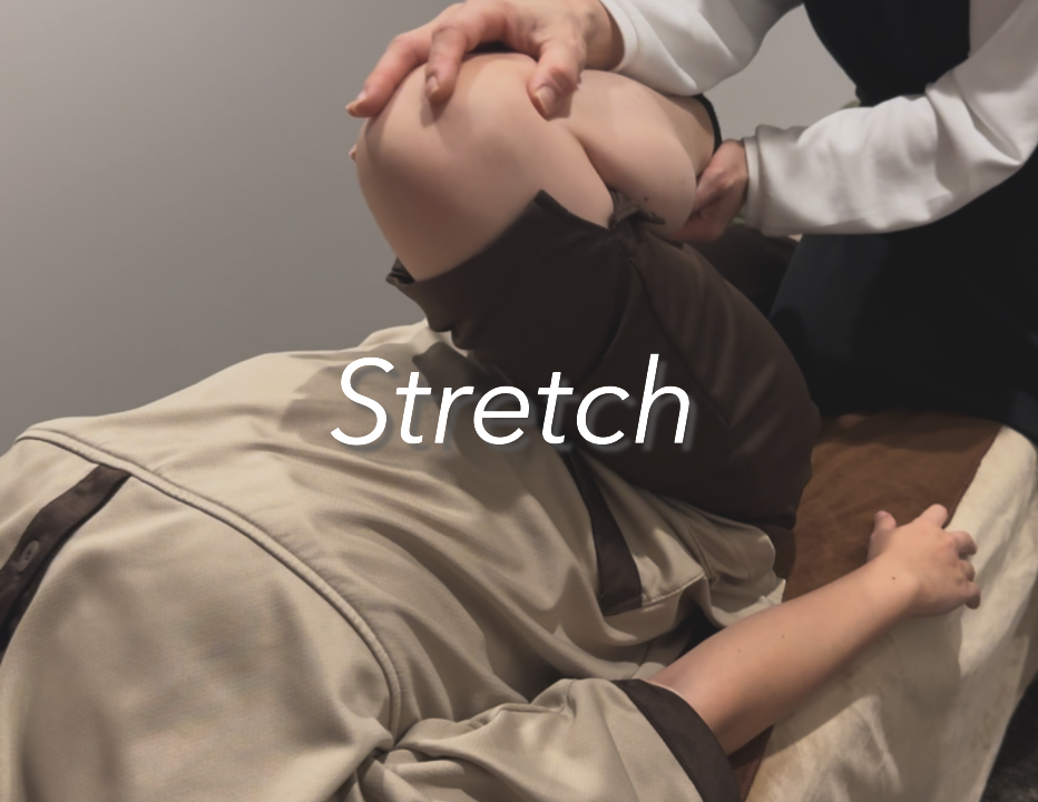 人がベッドに横になってストレッチをしている様子を医者がサポートしている。