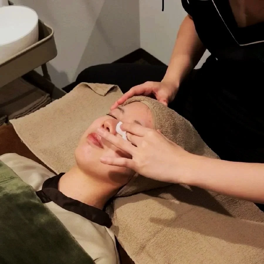 顔に乳白色のクリームを塗るために、鼻の下を指で拭う女性の様子