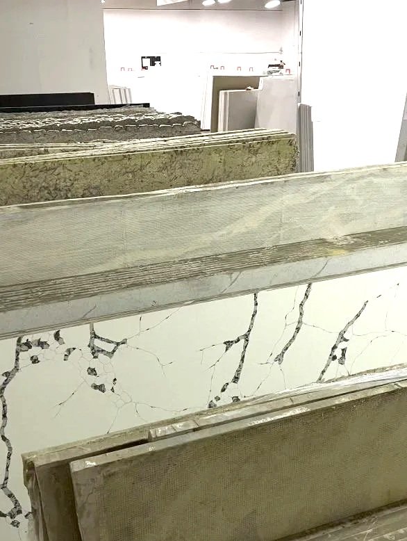 Various slabs of marble and stone tiles in an indoor showroom, standing vertically on display.