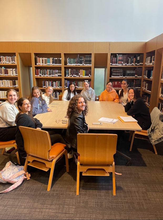 Group of students sitting around a large table in a library.