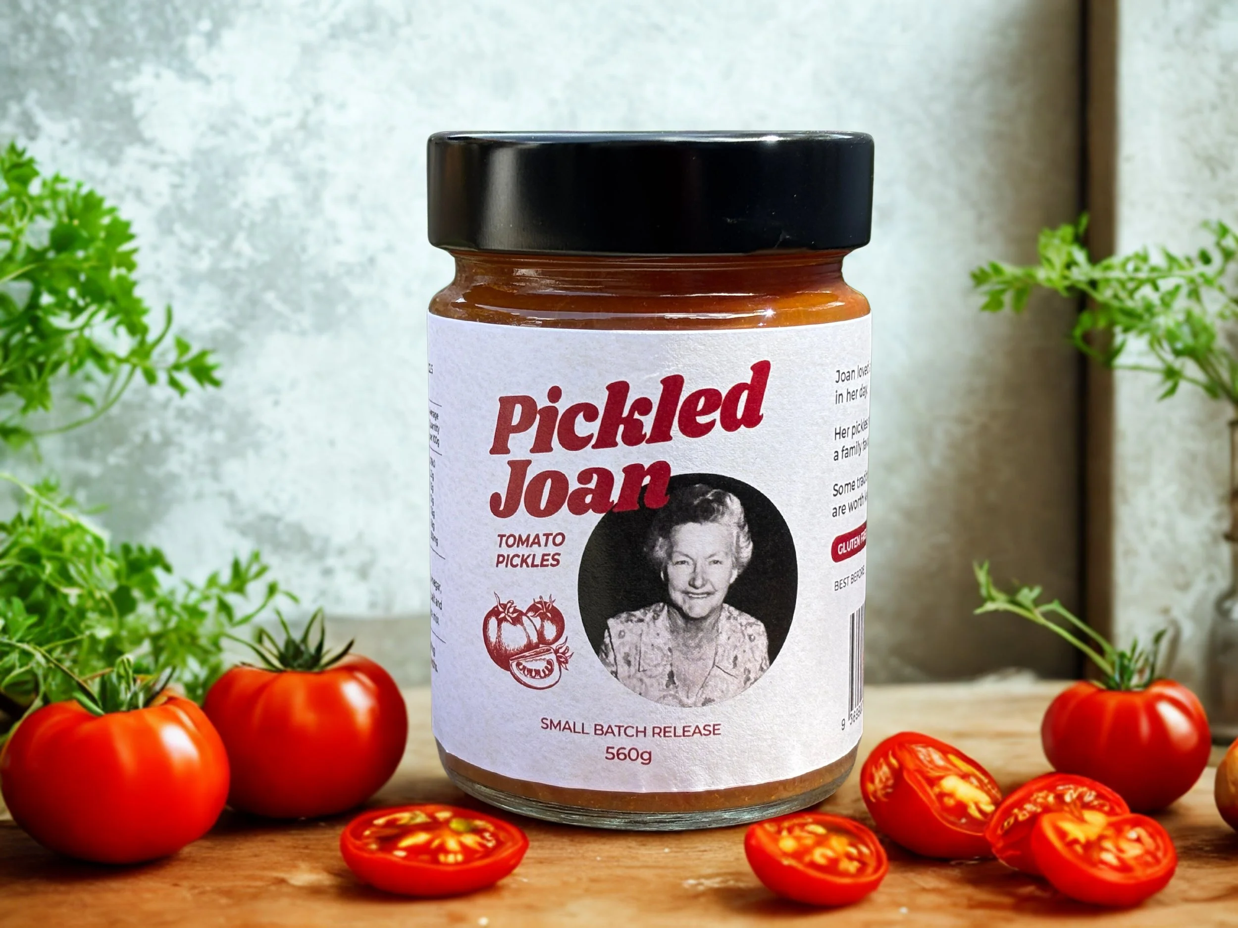 Product image on wooden bench with tomatoes and herbs around it. Jar shows product label details.