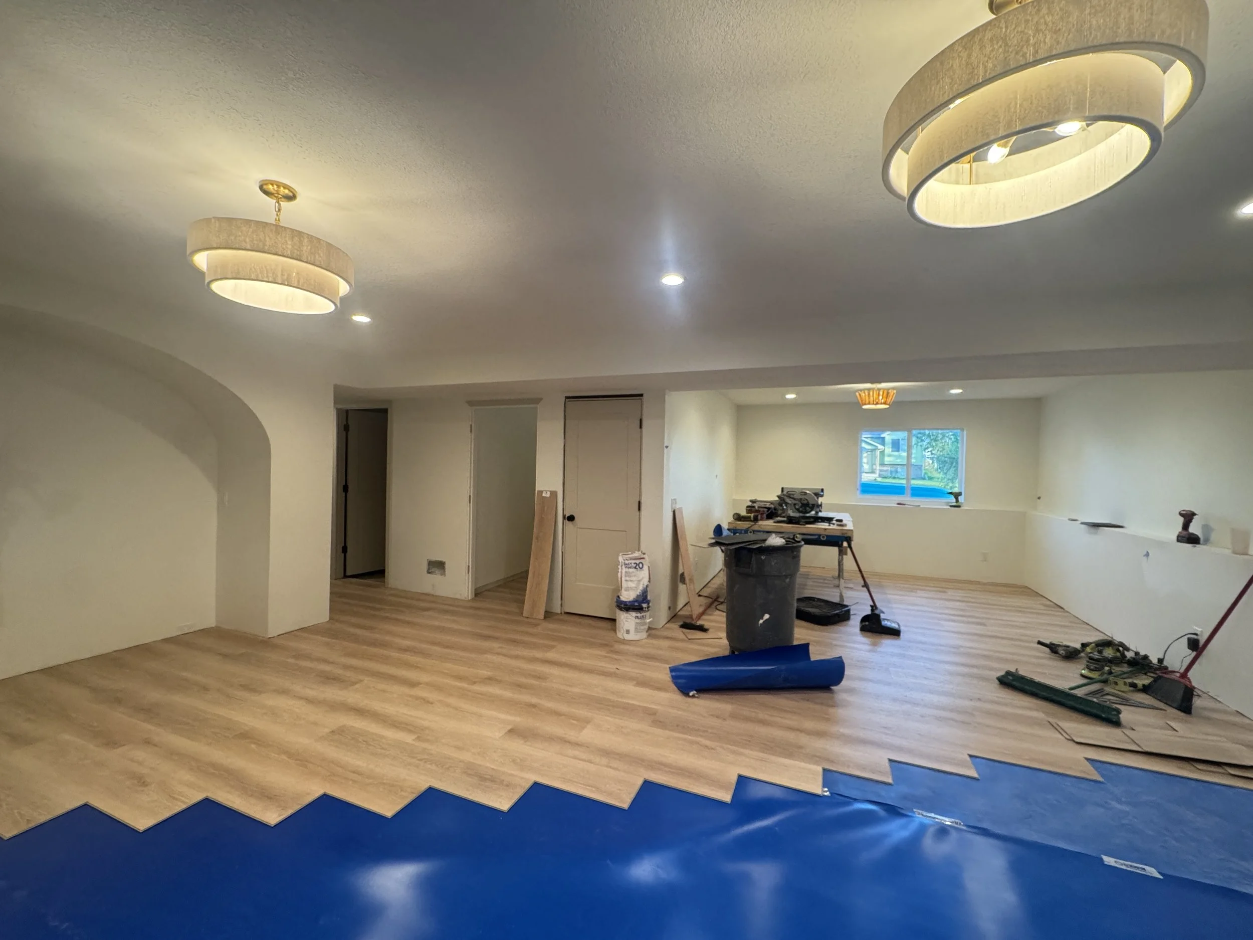 Light wood toned LVP flooring being installed on top of foam underlay with warm neutral walls