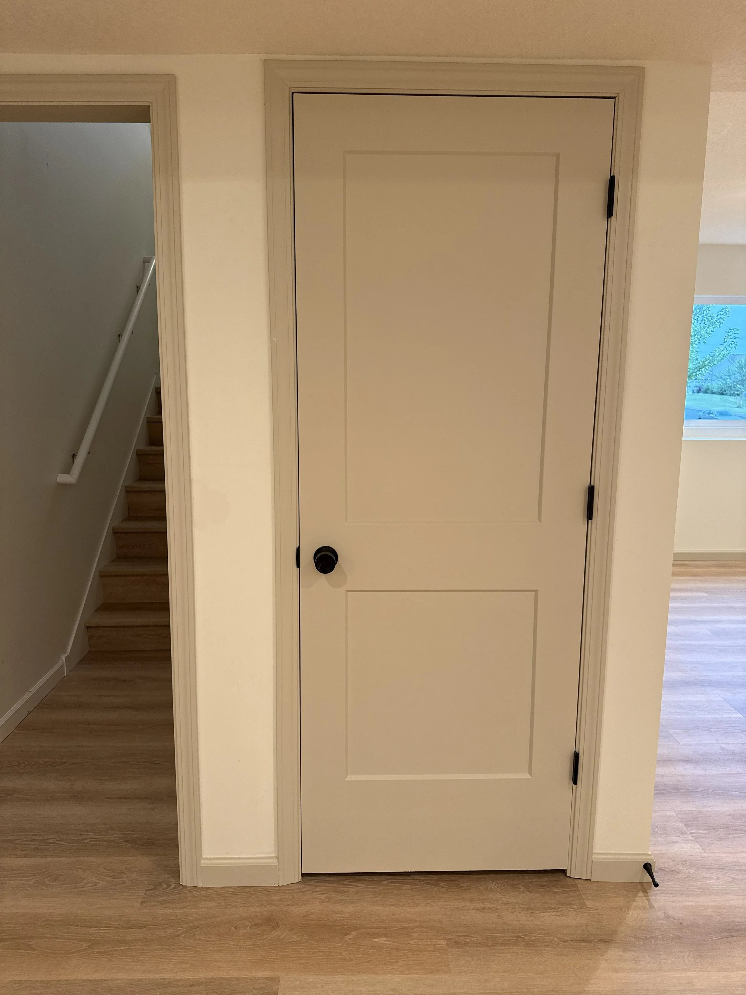 Doors painted in Sherwin Williams Accessible Beige with matte black door knobs and hinges and walls in Sherwin Williams Swiss Coffee