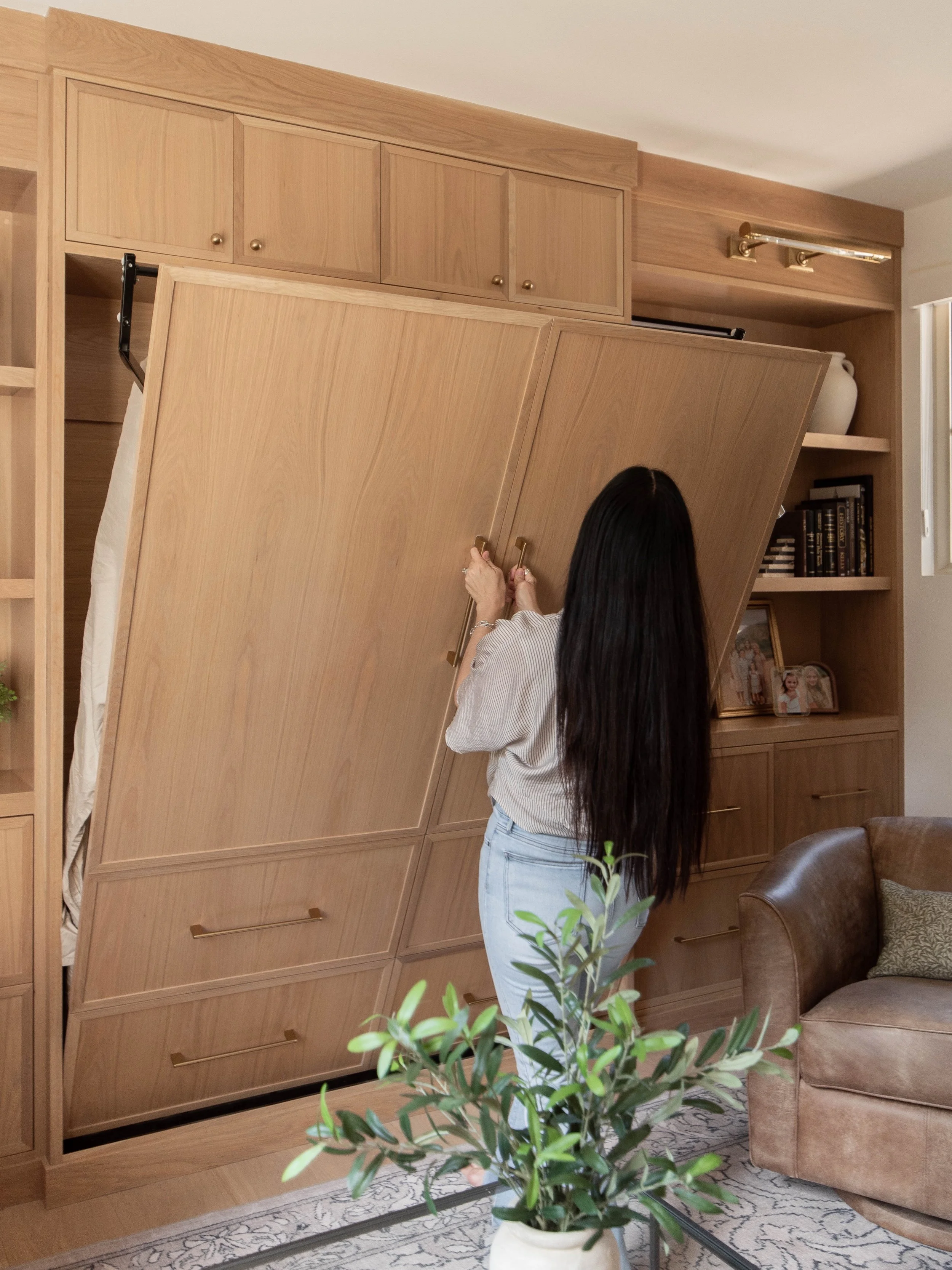 Storage is always front and center when we reimagine a space. 
Every item needs a home, every corner needs a purpose. In this living room-meets-office, a built-in Murphy bed tucks away into the wall when it&rsquo;s not in use, and curated wall storag