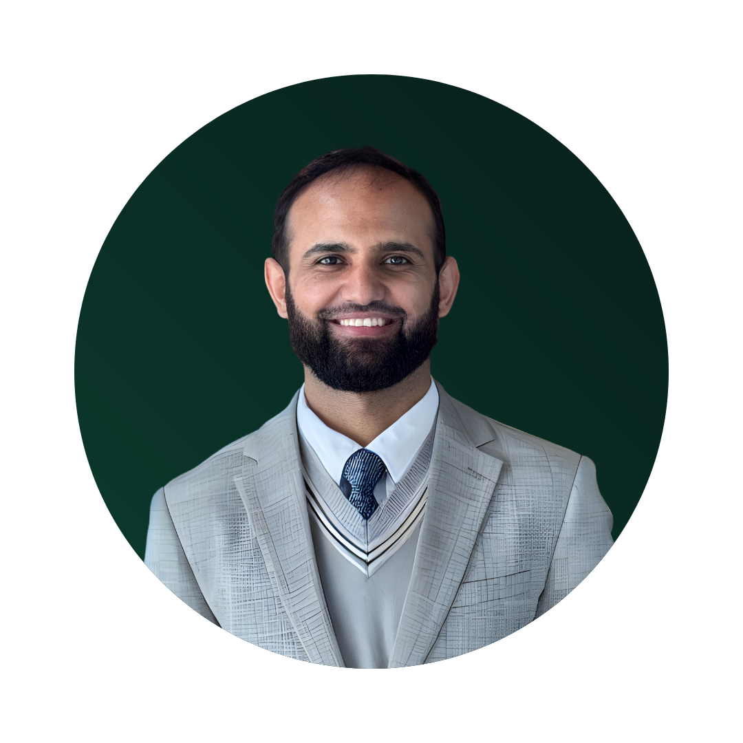 Headshot of a smiling man with a beard in a light grey suit, white shirt, and blue patterned tie, against a dark green background.