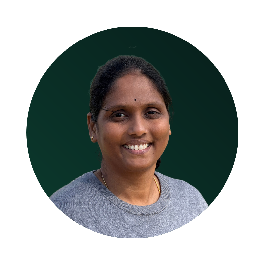 A woman with dark hair, smiling, wearing a grey top and small earrings, against a dark green background.