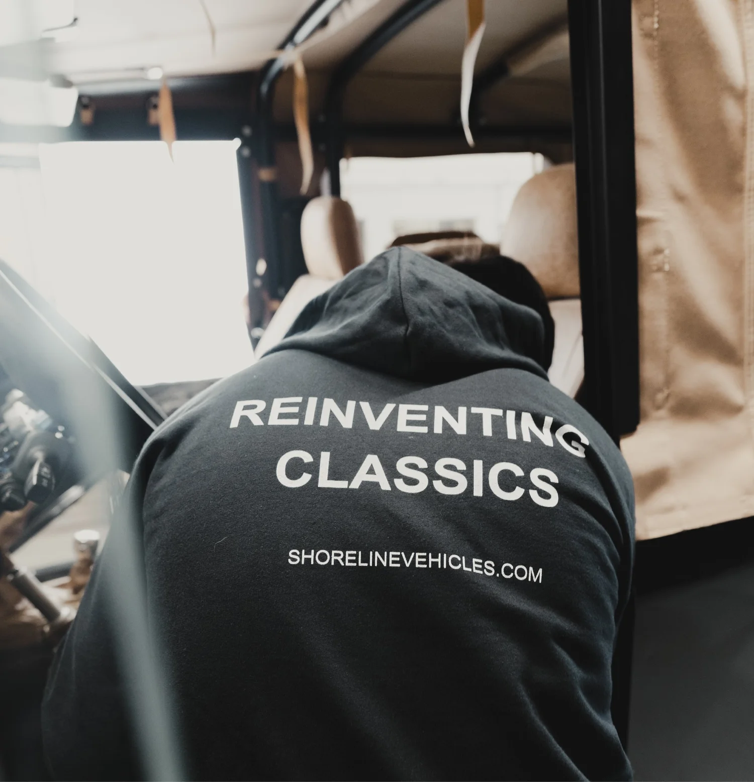 Shoreline builder in a Reinventing Classics hoodie working inside a Defender