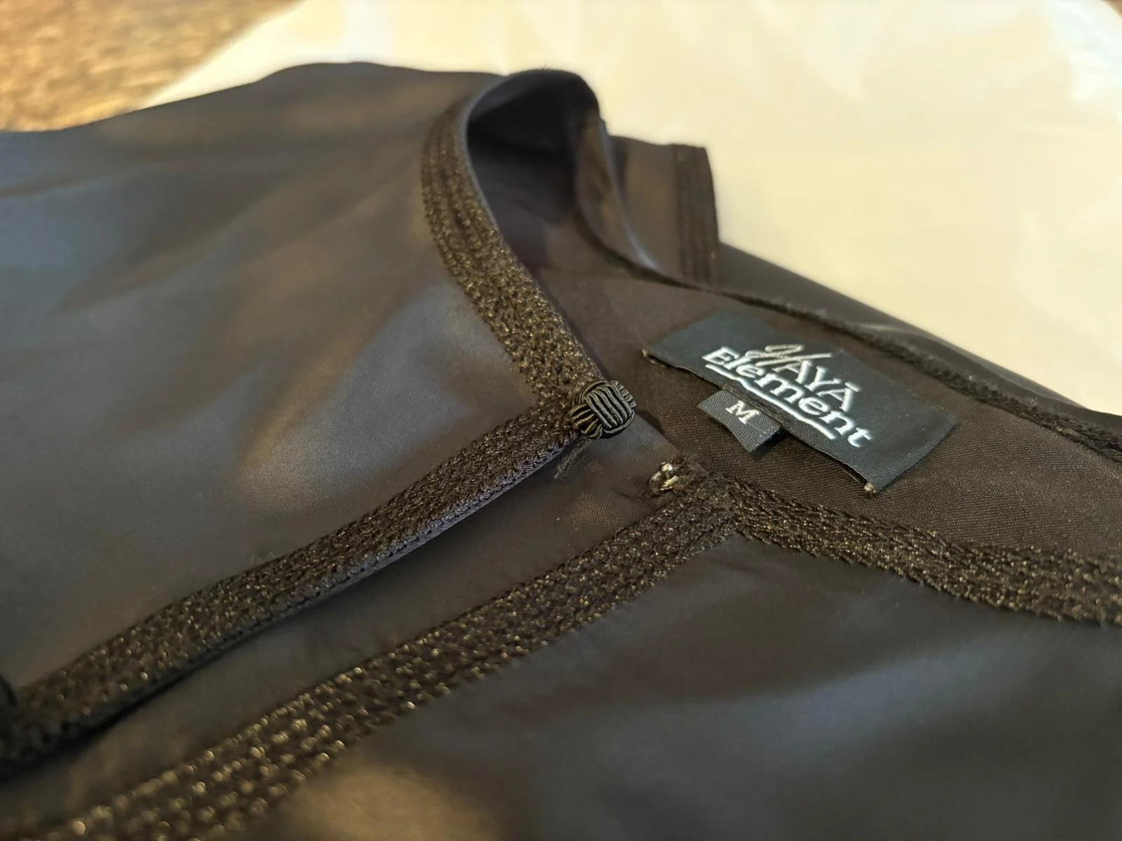 A black piece of clothing or gear with a zipper, looking like a jacket or bag, with a visible tag that reads 'WASHAWEAR' and an