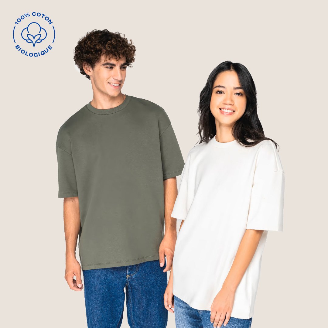 Deux personnes portent des t-shirts en coton biologique de couleur unie, l'homme porte un t-shirt vert olive et la femme un t-shirt blanc, sur un fond beige, avec un logo indiquant '100% coton biologique'.