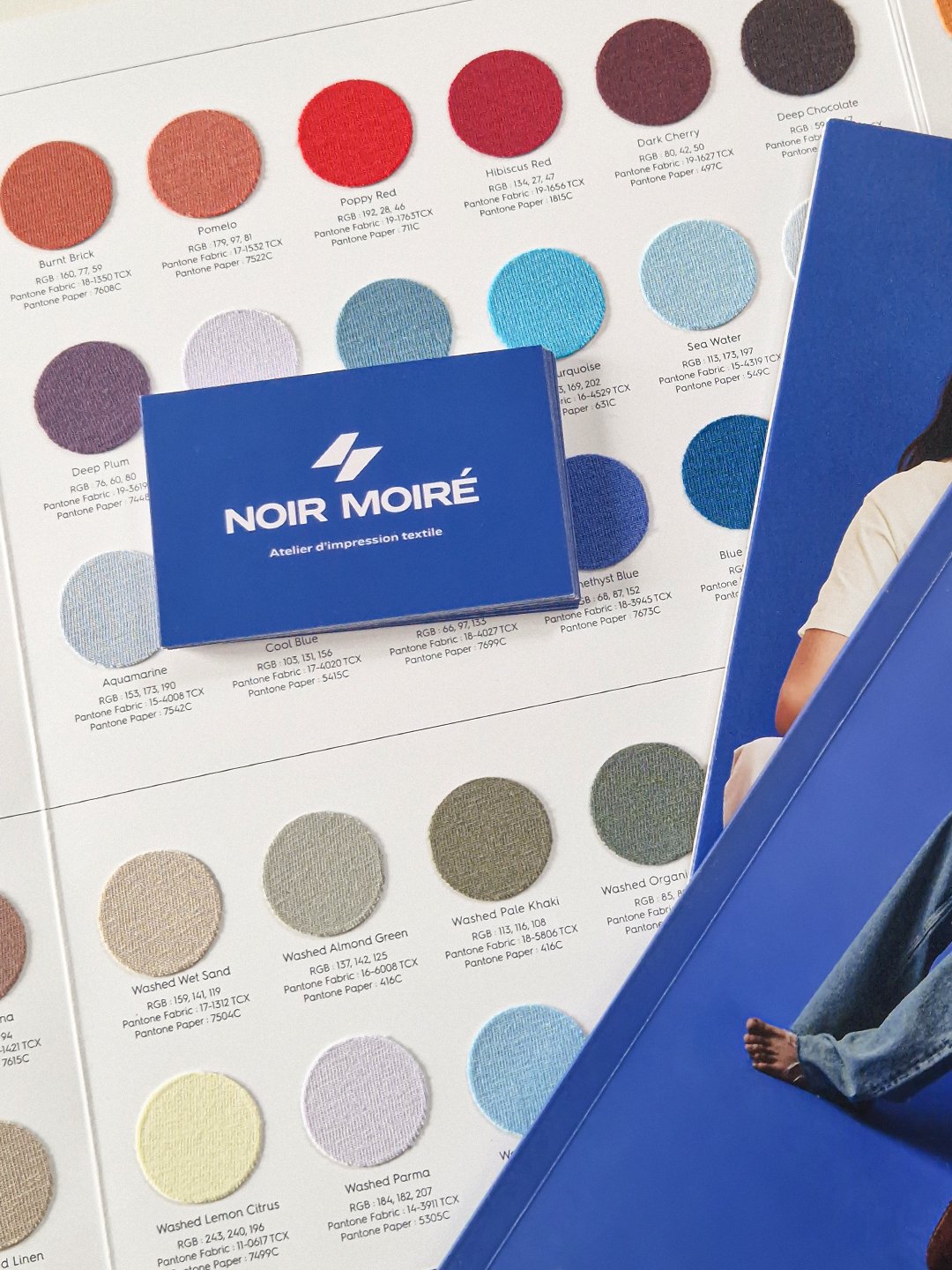 Échantillon de couleurs textiles avec une boîte bleue portant le logo 'Noir Moiré'.