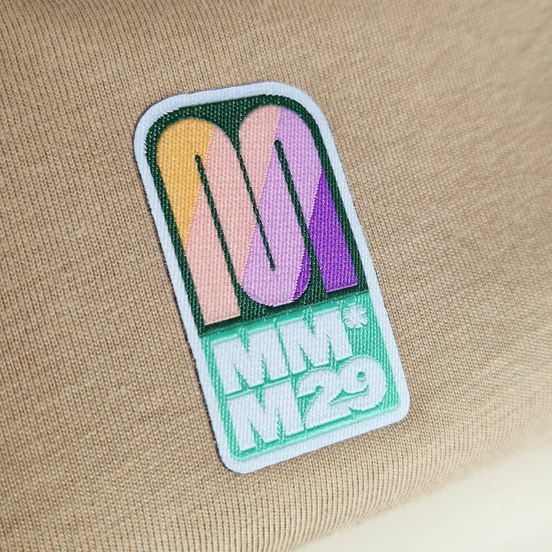 Écusson brodé avec le logo 'OK' coloré sur fond beige