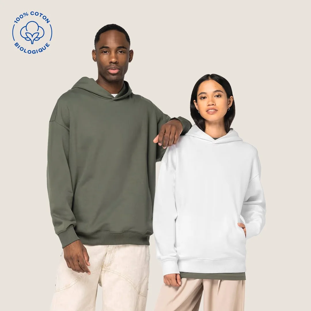 Deux personnes portent des sweat-shirts à capuche, l'un vert et l'autre blanc, sur un fond beige. Un logo indique que le vêtement est 100% coton biologique.