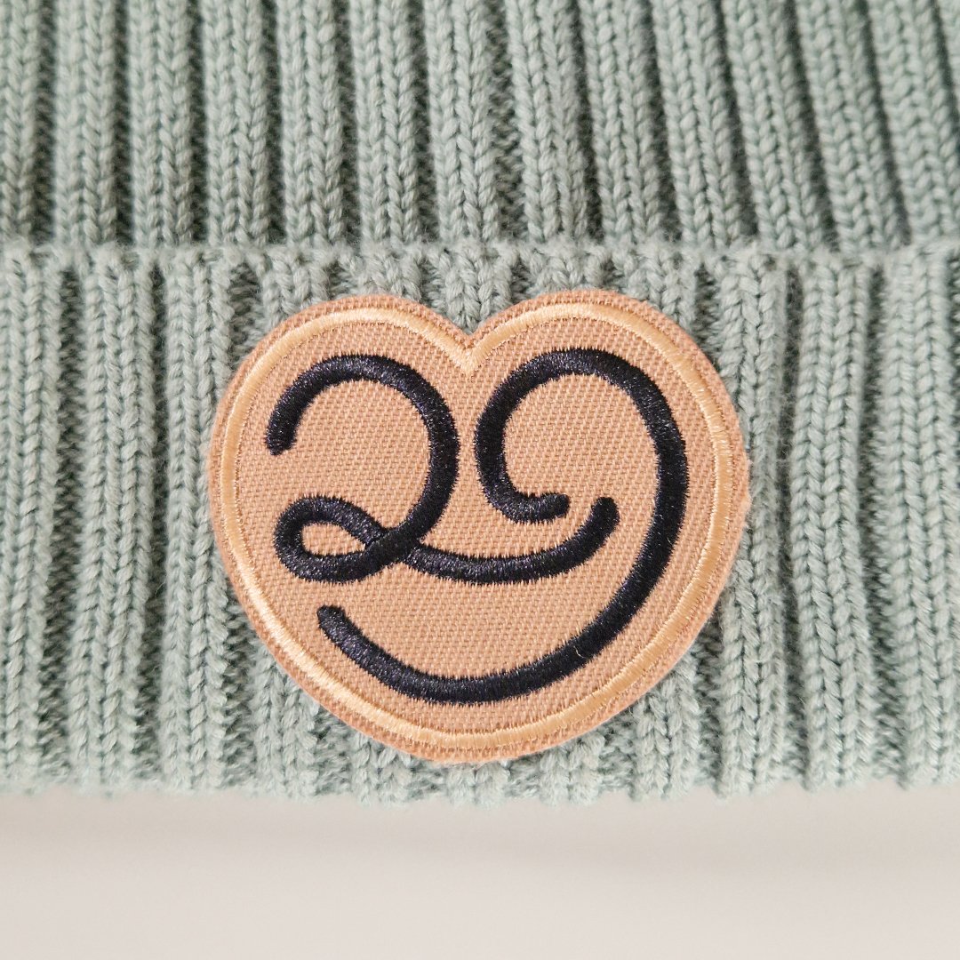 Coussin en tricot gris avec un patch brodé en forme de cœur souriant