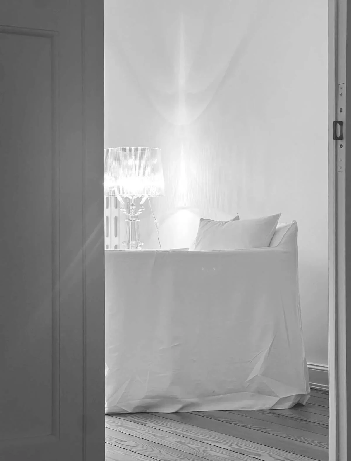 Blick durch eine geöffnete Tür in einen hellen Coaching-Raum mit Sessel und Tischlampe