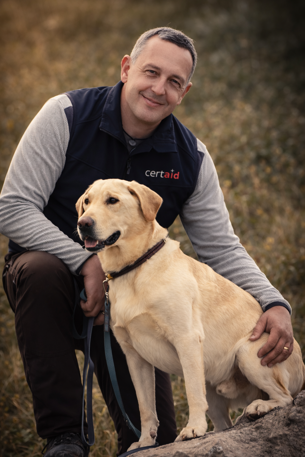 Der Hundeführer und Geschäftsführer Matthias Knöri mit seinem Rettungshund Kenai. Kenai trägt eine Kenndecke und einen Bringsel an seinem Halsband.