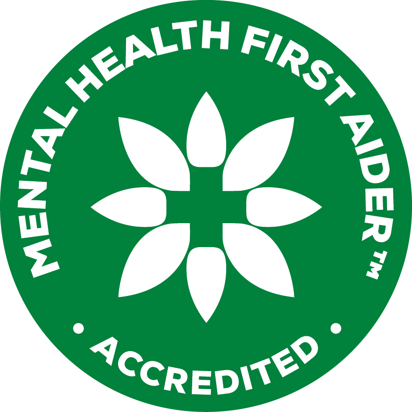 Green circular badge with white text that says 'MENTAL HEALTH FIRST AIDER ™' and 'ACCREDITED.' The center features a white stylized flower with eight petals.