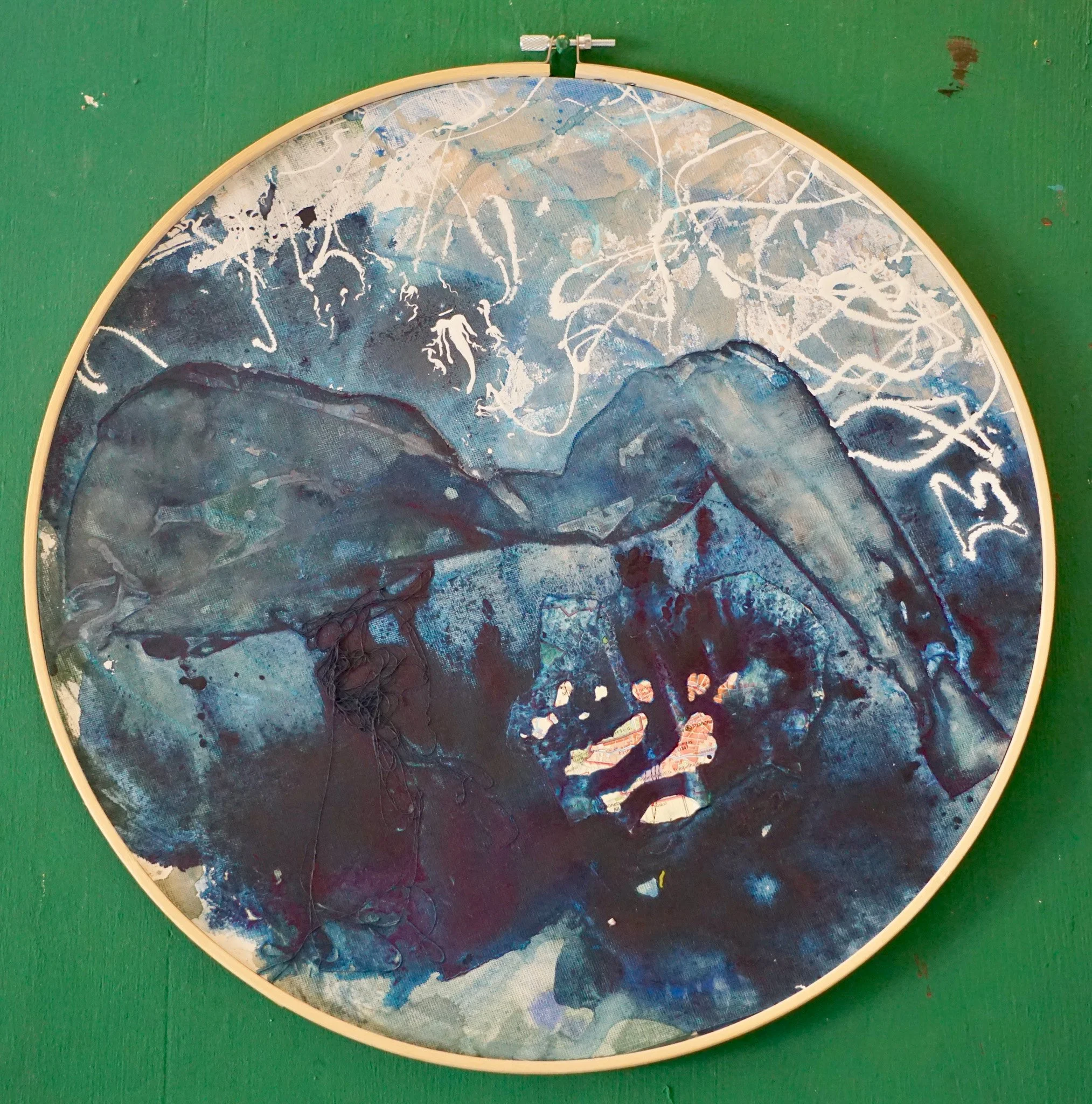 Abstrakte Kunstdruck in Blau- und Schwarztönen mit weißen Akzenten, eingebettet in einen runden Rahmen auf grünem Hintergrund.