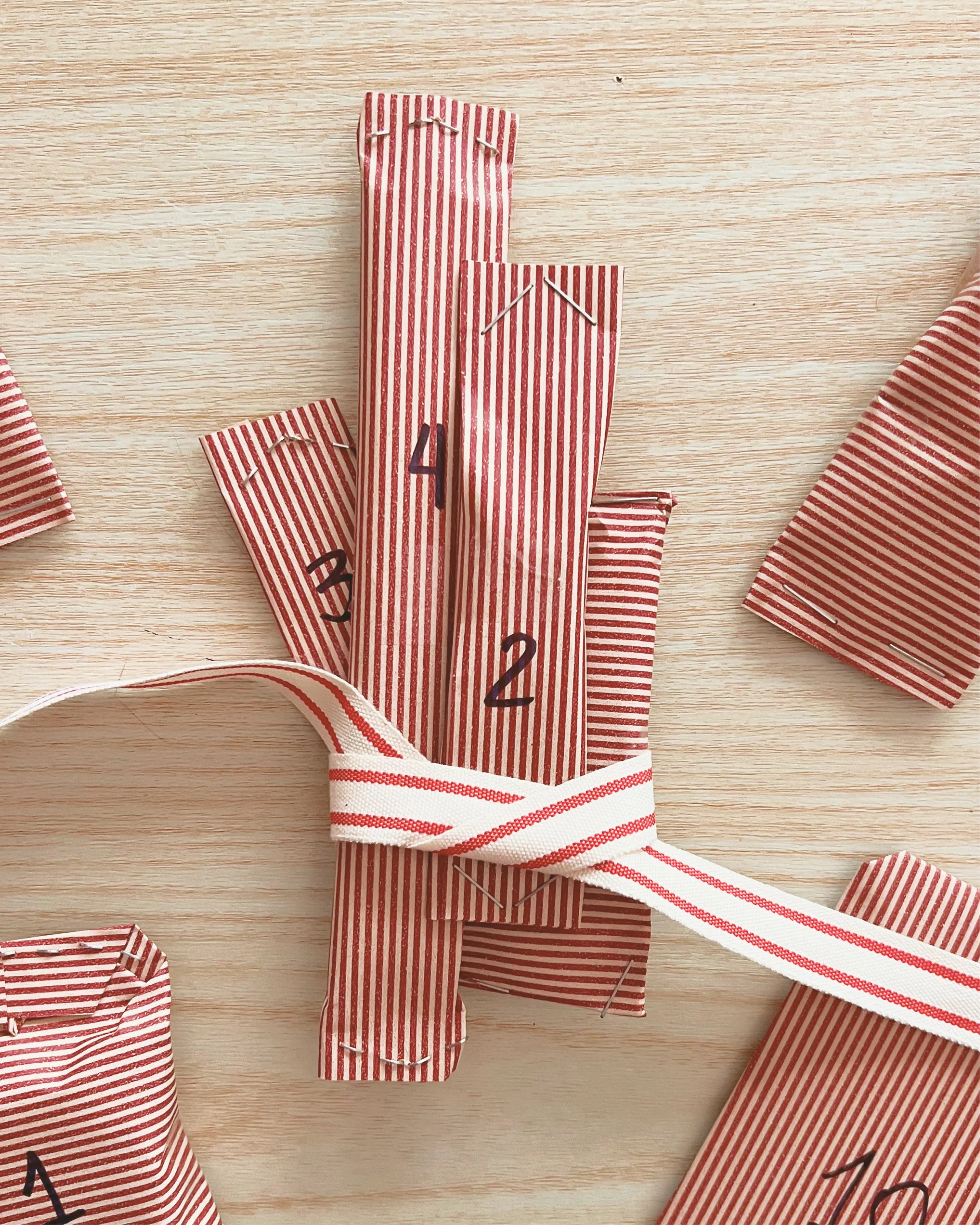 Bundle of small, red-striped parcels tied with a cream-and-red ribbon.jpg