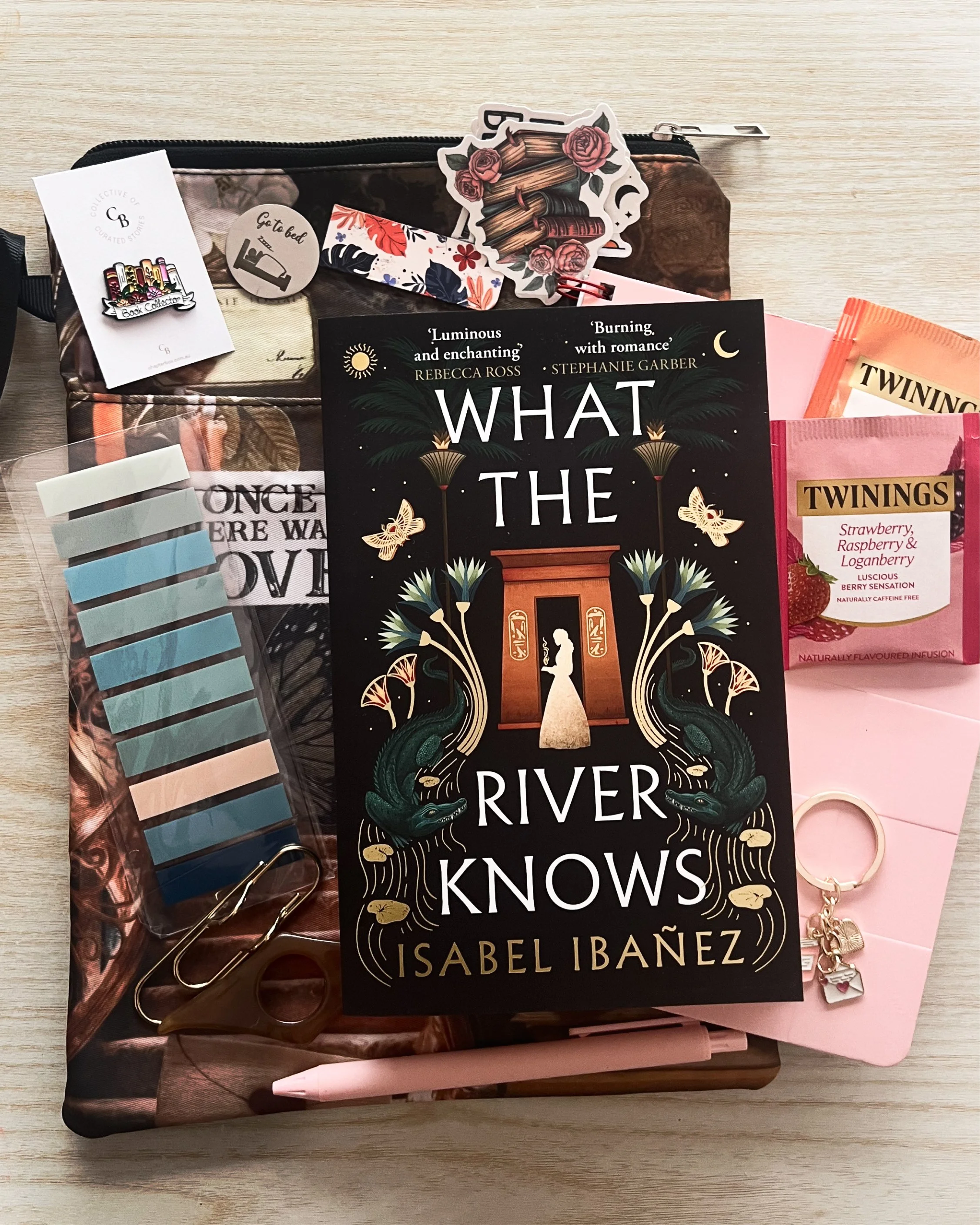 Top view of book, notebook, pen, tea, book tabs, keychain and bookmark