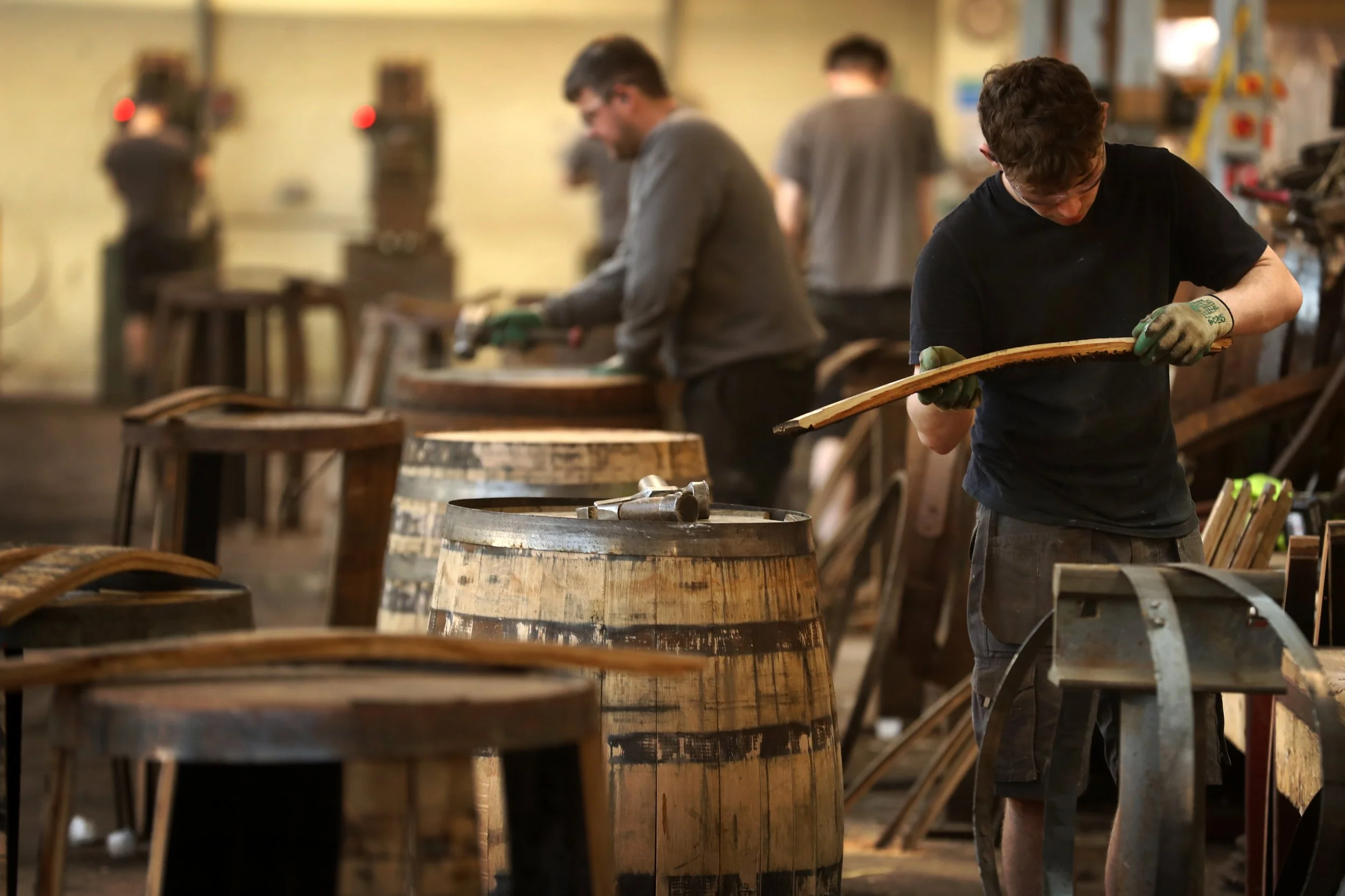 Coopers working at Oakwood Cooperage workshop crafting casks with wood and tools.