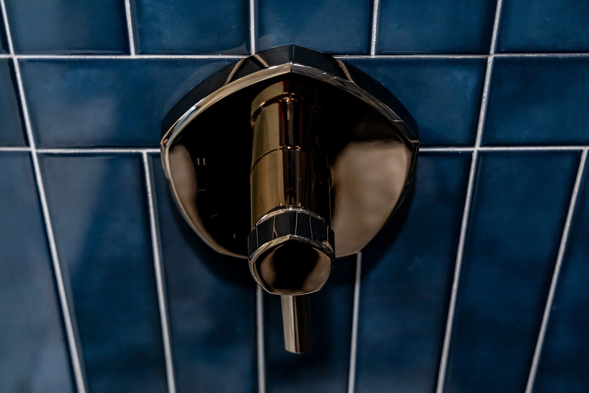 Kohler Occasion pressure balanced valve trim in Vibrant French Gold on blue vertical tile