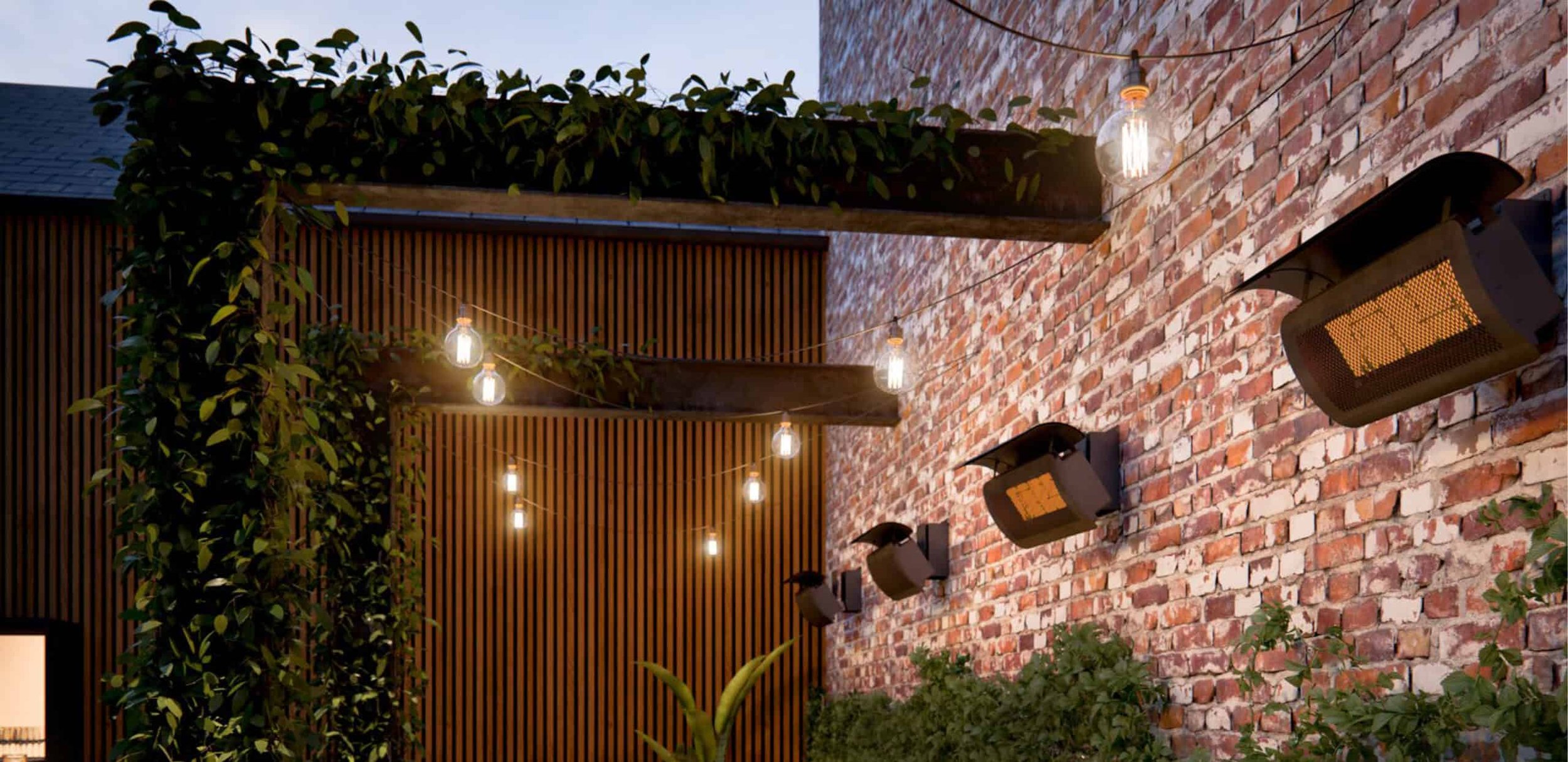 Outdoor patio area with string lights hanging overhead, brick wall with mounted heaters, greenery, and wooden decor accents.