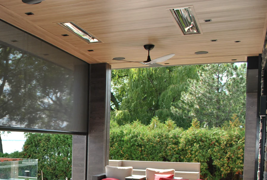 Indoor patio with wooden ceiling, ceiling fan, large window, and outdoor greenery with trees.
