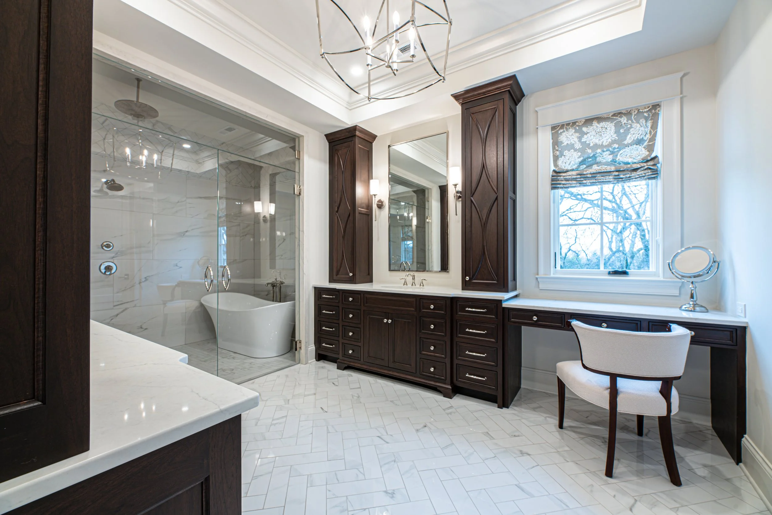 Luxury bathroom with dark wood cabinetry, marble floor, and a window with a patterned Roman shade.