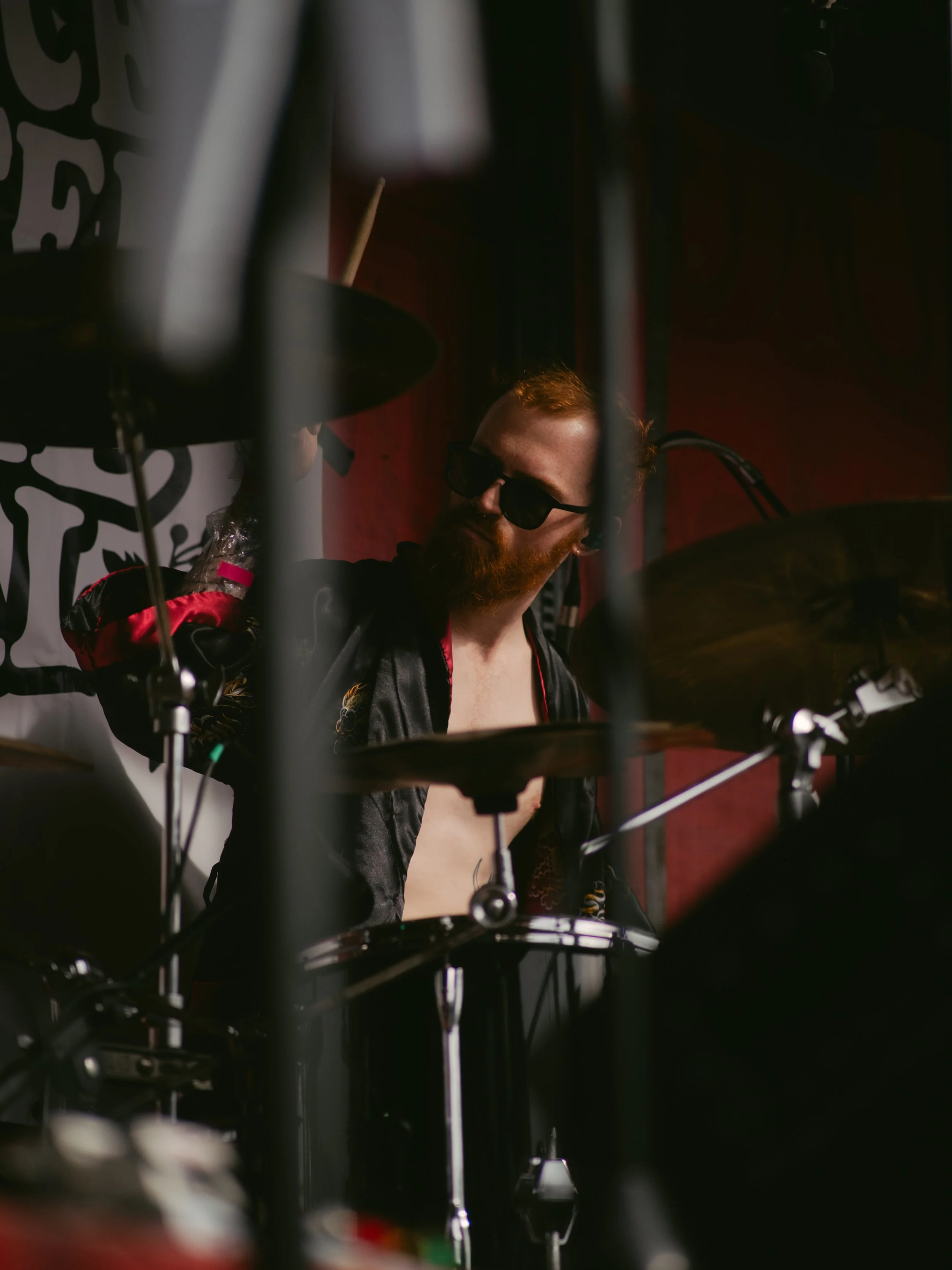 A man with a beard and sunglasses playing drums on stage.