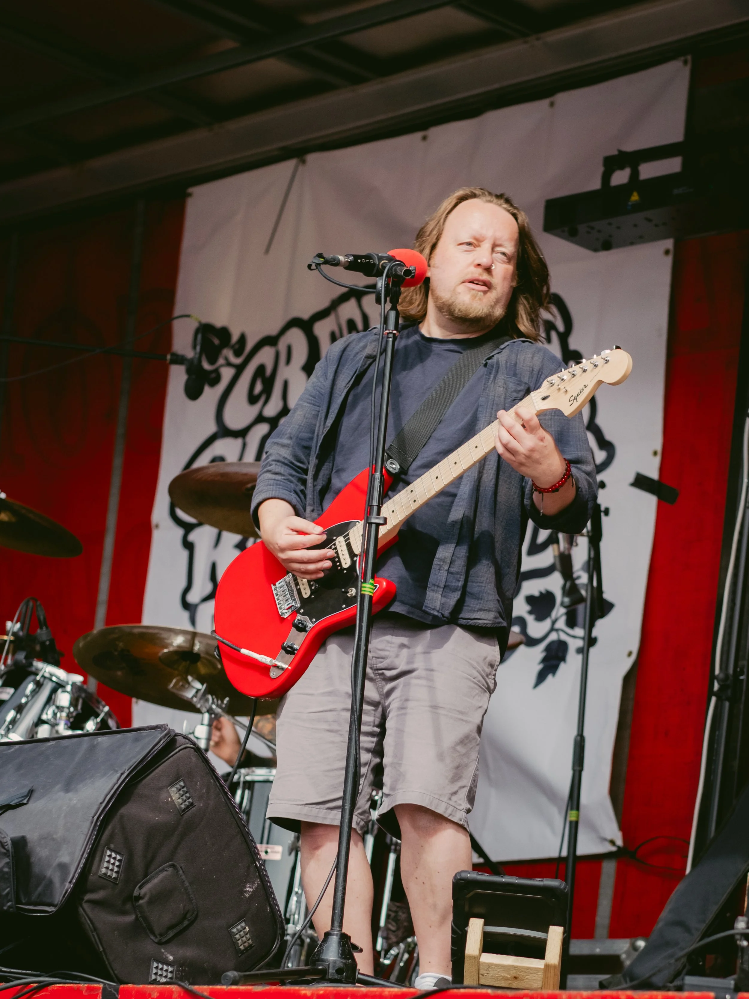 A man with shoulder-length hair playing an electric guitar on stage during a live performance.
