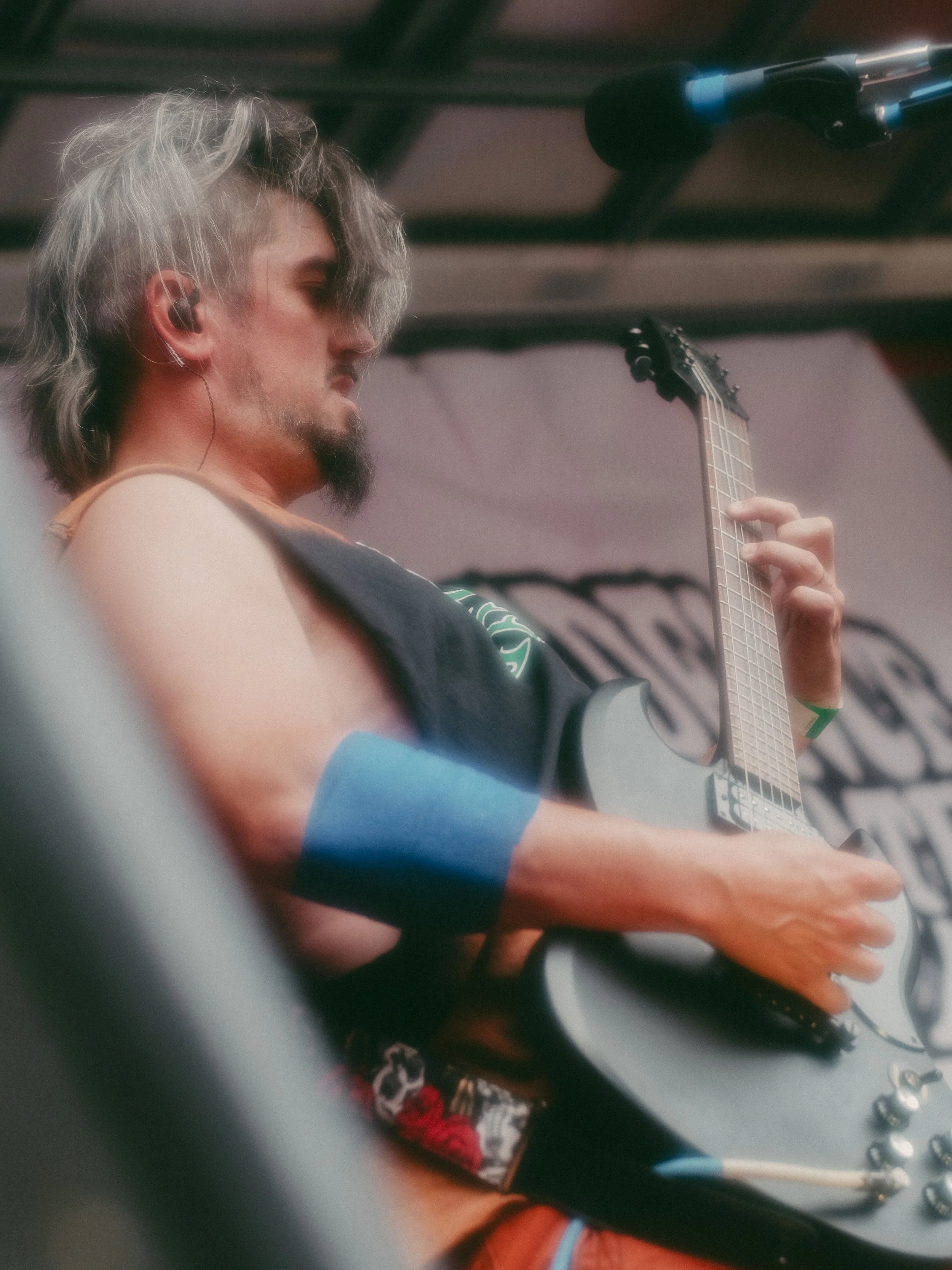 A male guitarist performs on stage, playing an electric guitar with a focused expression.