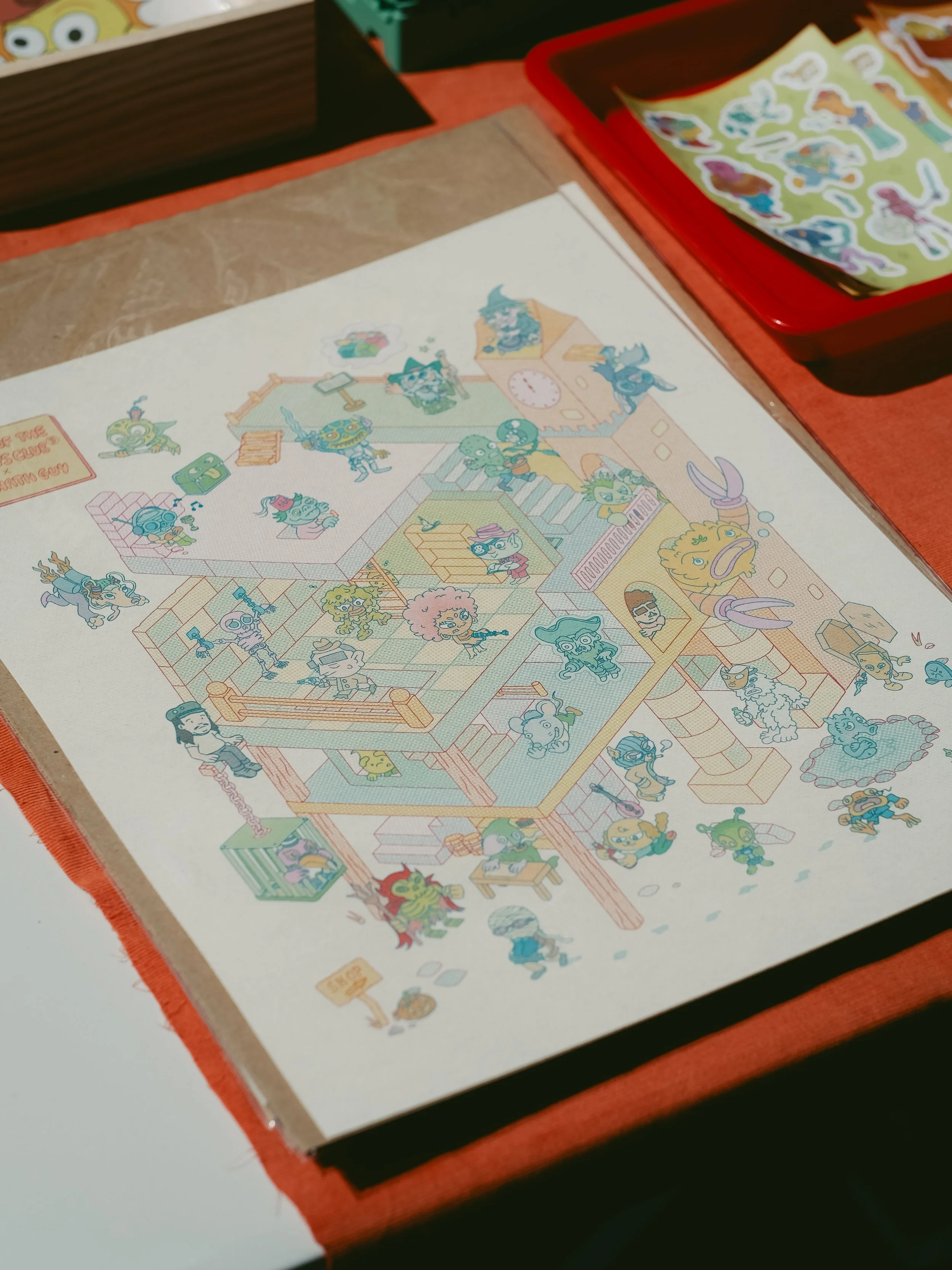 Colorful illustrated map of a whimsical, multi-story building with various cartoon characters and creatures on each floor, set on a table with stickers and other craft supplies nearby.