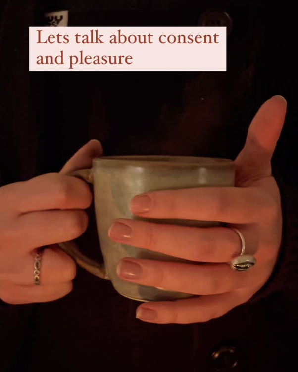A person holding a ceramic mug with both hands, wearing rings on fingers, with text overlay that reads 'Let's talk about consent and pleasure'.