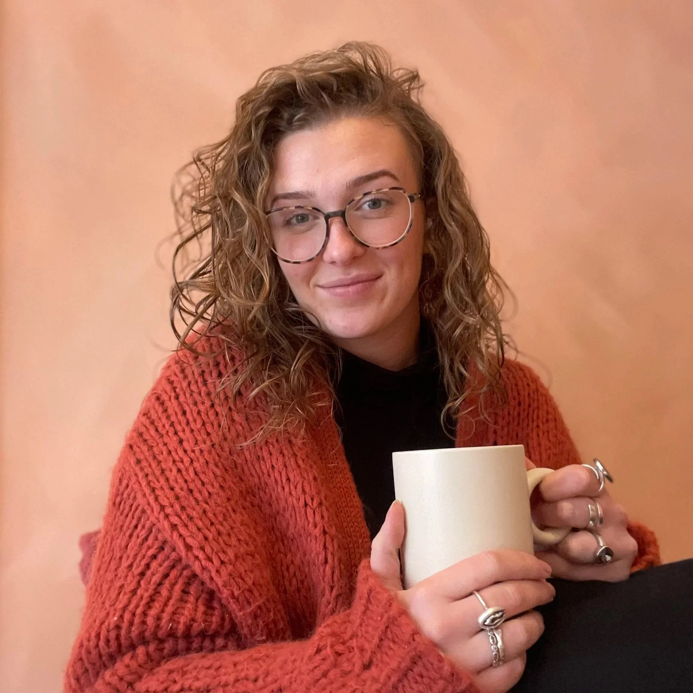 Sarah Peart, Brisbane sex therapist, smiling warmly with a mug in a relaxed and approachable portrait