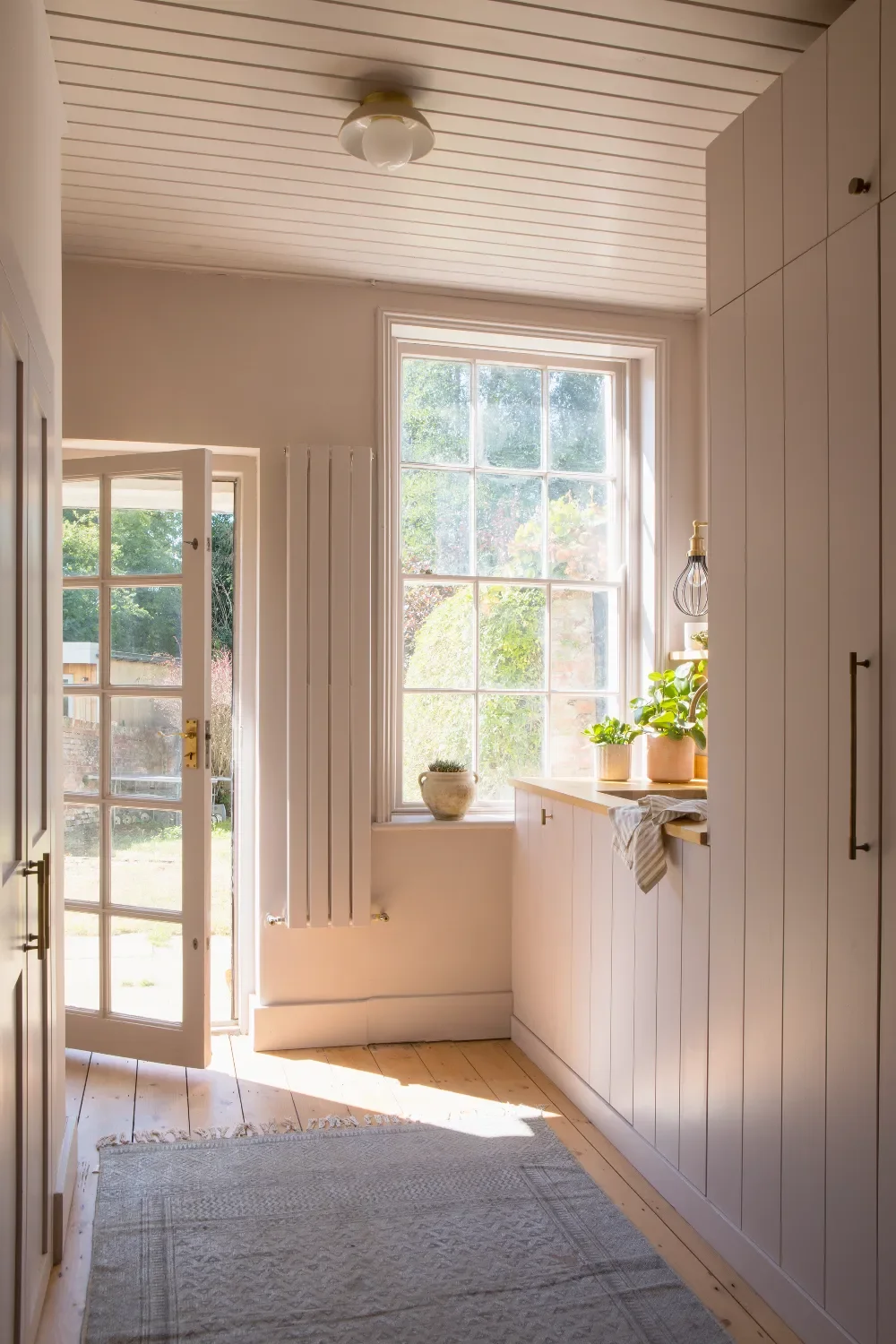 Pink-laundry-room-with-rug-and-garden-view-interior-design-kent-michelle-shakallis.webp