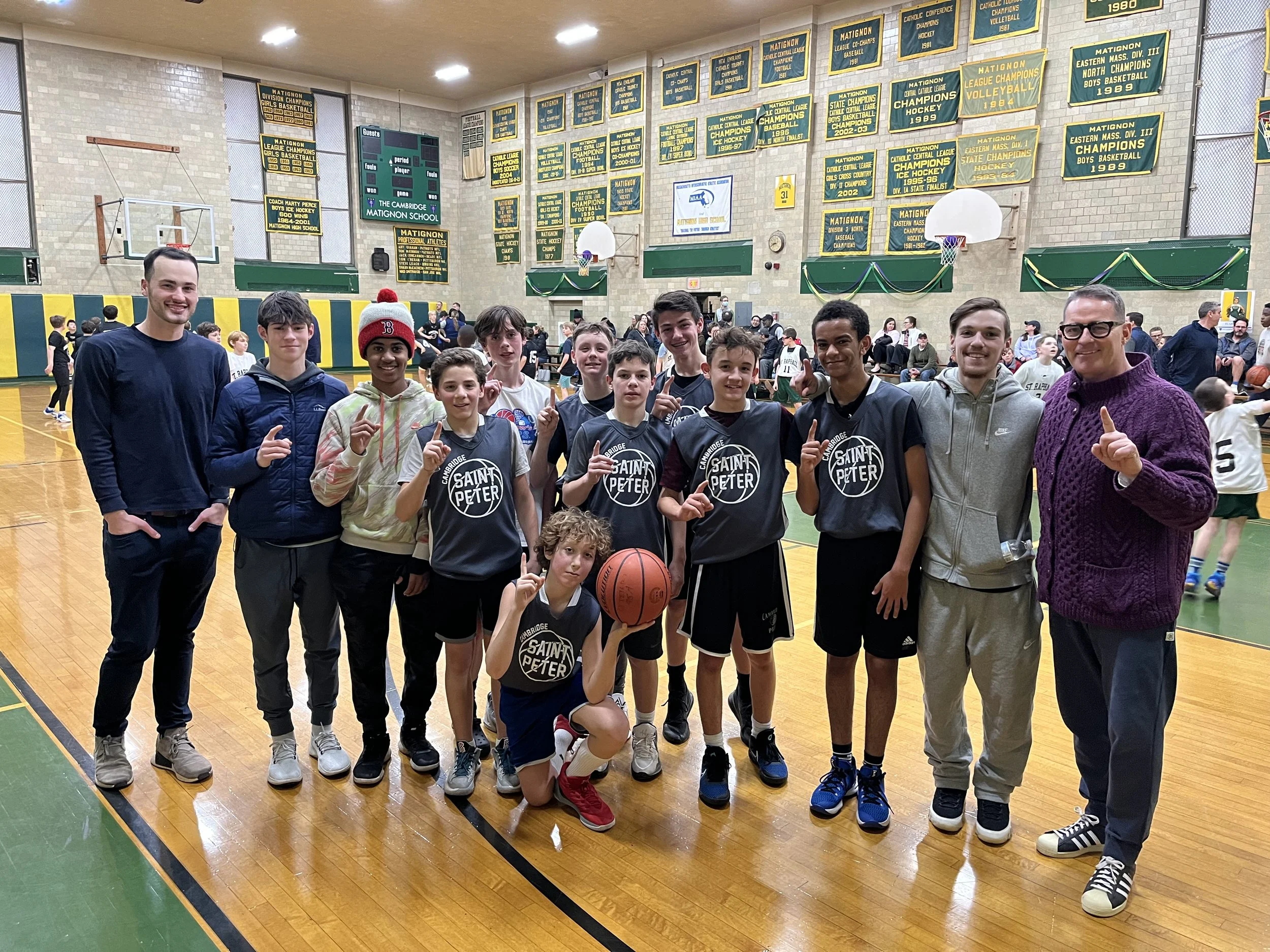 Coach Tim Flaherty and his St. Peter's CYO basketball team posing in a gymnasium after a game, some holding a basketball, with banners and a scoreboard in the background.