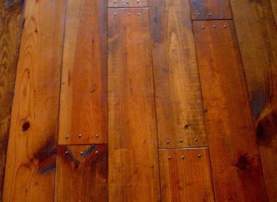 Close-up of wooden floorboards with visible wood grain and small metal nails.