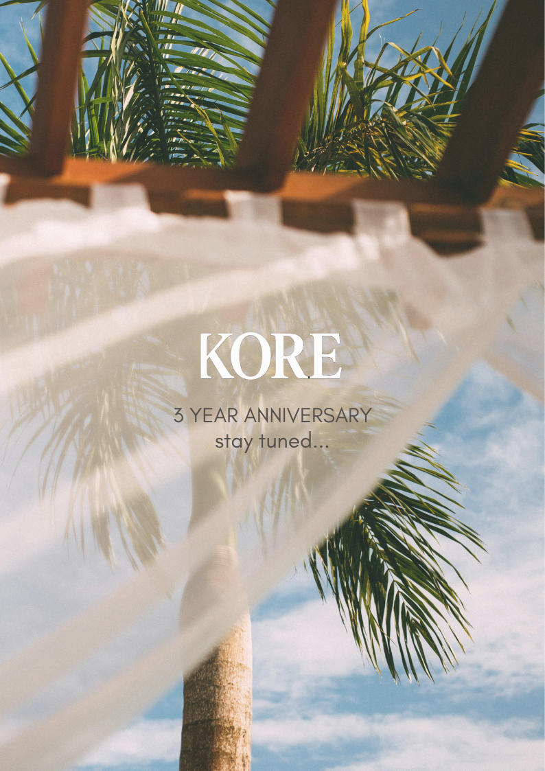 A tropical hut with a thatched roof, a wooden door, lush greenery on the side, and a welcome mat that says "Welcome". Text on the image says "KORE" at the top and "1 YEAR ANNIVERSARY stay tuned..." at the bottom.