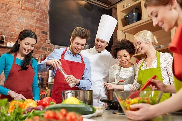 Chef teaching a diverse group of adults during a hands-on cooking class.