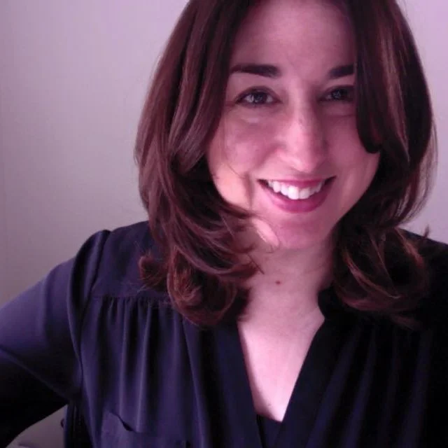 Brown haired woman wearing a black shirt smiles.