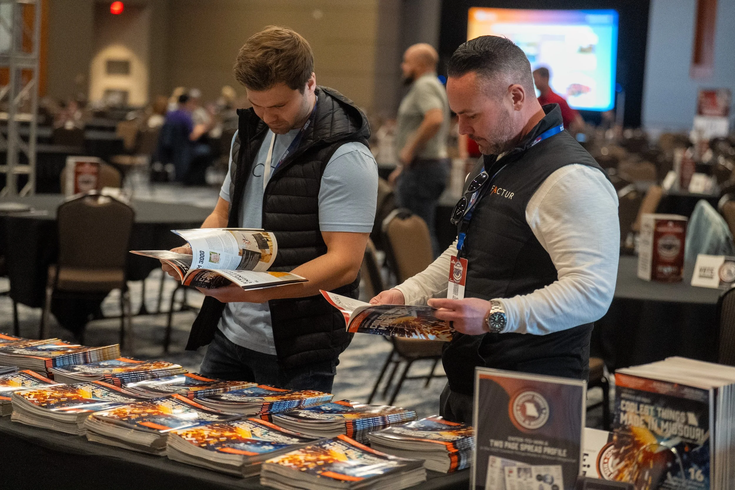 two men looking through Coolest Things Made in Missour magazine at the live event