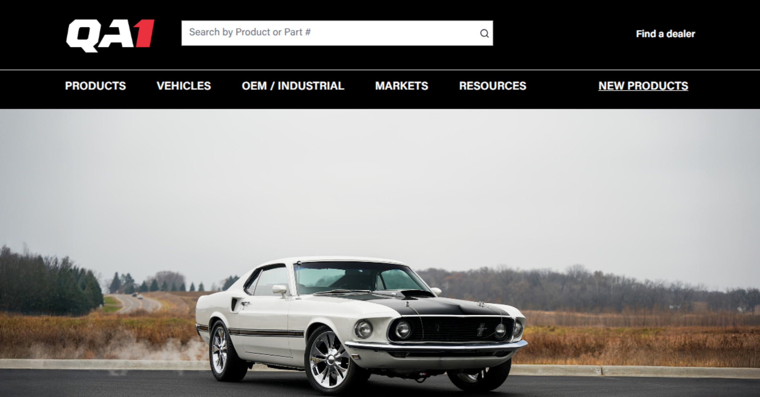 A classic white muscle car with black racing stripes driving on a highway through a rural landscape.
