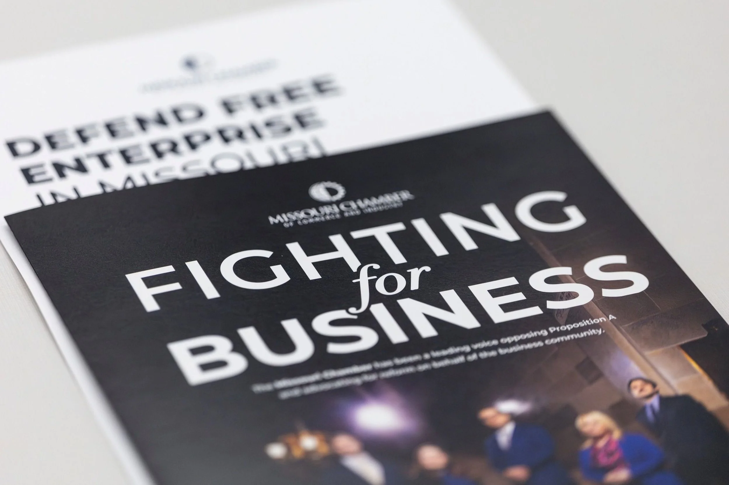Close-up of a flyer with the title "Fighting for Business" and an image of people in formal clothing.