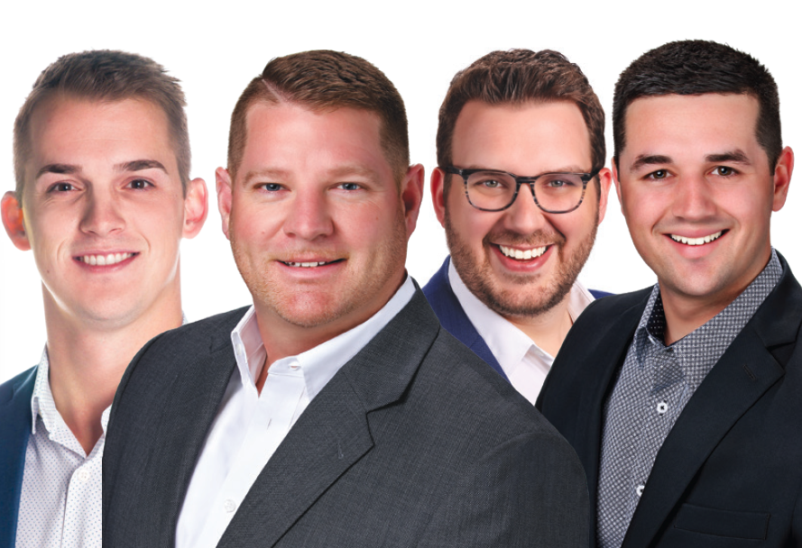 Four men in business suits smiling in a group photo