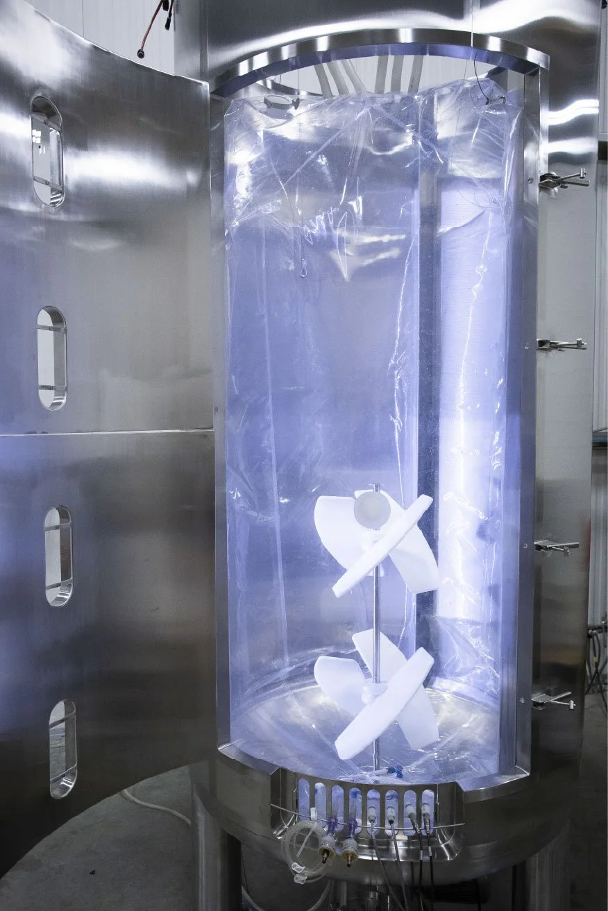 A laboratory sterilizer chamber with a plastic bag inside, containing a white orthopedic brace or medical support device, illuminated by blue light.