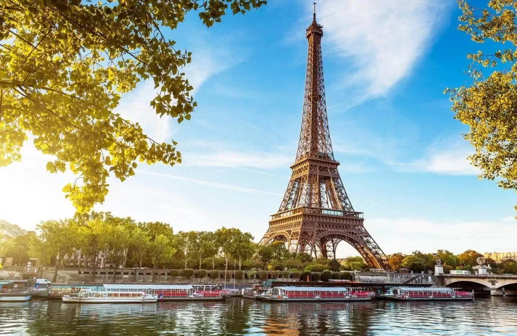 Eiffel Tower in Paris view from river with boats and trees