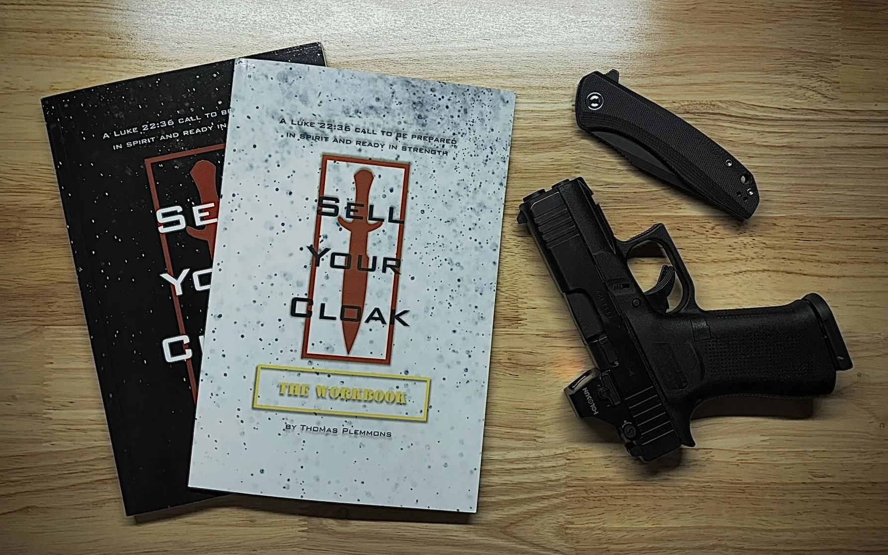 Sell Your Cloak book and Sell Your Cloak: The Workbook by Thomas Plemmons, a Glock 43X  and a Civivi folding knife on a work bench.
